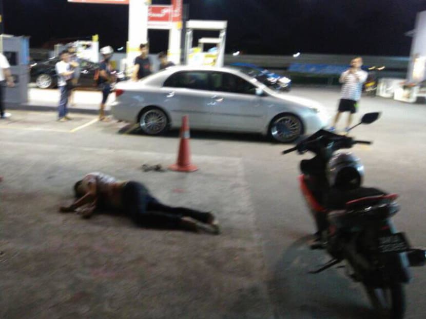 A male motorist lies unconscious at a Shell petrol station along Jalan Sri Pelangi in Johor Baru after he was brutally attacked, stabbed and run over twice by his assailants. Johor police say they have arrested two people in connection with the case. Photo: Youtube screengrab