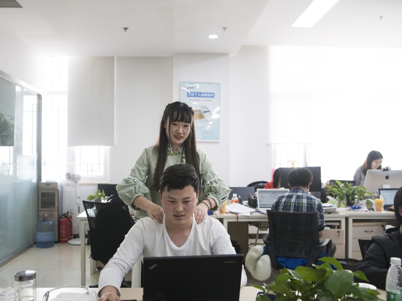 Ms Shen Yue massages the shoulders of one of her colleagues at Chainfin.com, a consumer finances company. “Programmer motivators” — women hired primarily to chat up and comfort overworked coders — have become common in China’s tech sector, where gender biases are rarely discussed and firmly entrenched.