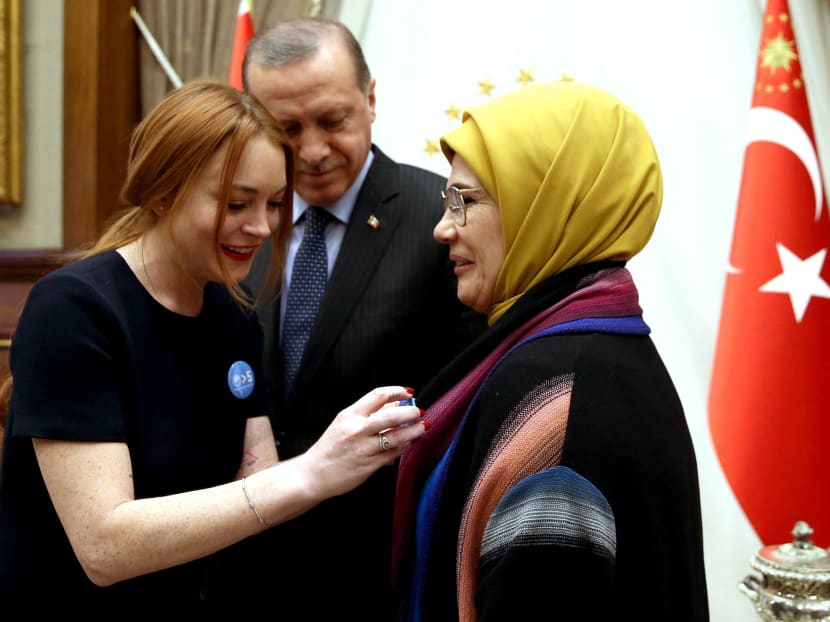 Handout photo taken and released by Turkey's Presidential Press Office on Jan 27, 2017 showing American actress Lindsay Lohan (left), flanked by Turkish President Recep Tayyip Erdogan  putting a badge on the jacket of Turkish President's wife Emine Erdogan during her visit at the presidential palace, in Ankara. Photo: AFP