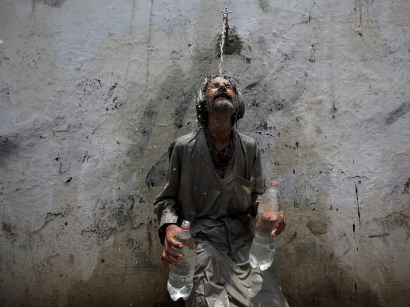 A man cools off from a public tap after filling bottles during intense hot weather in Karachi, Pakistan, June 23, 2015. Photo: AFP