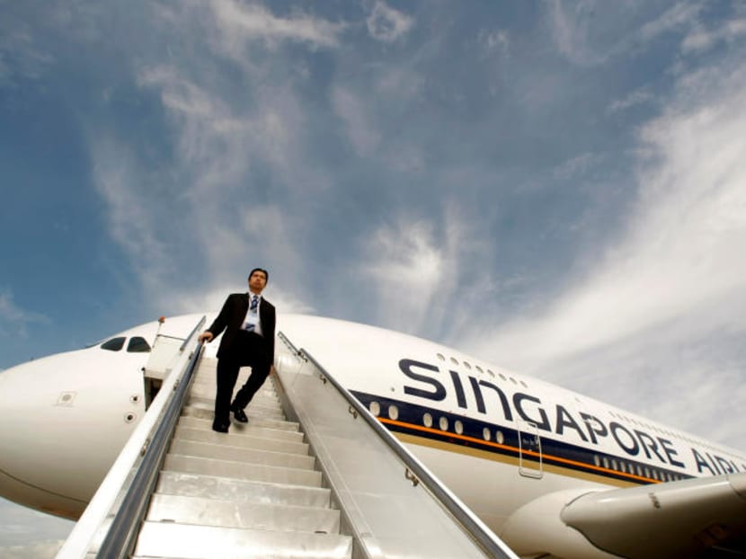 A Singapore Airlines staff member walking down a set of stairs from an Airbus A380 at Sydney International Airport.