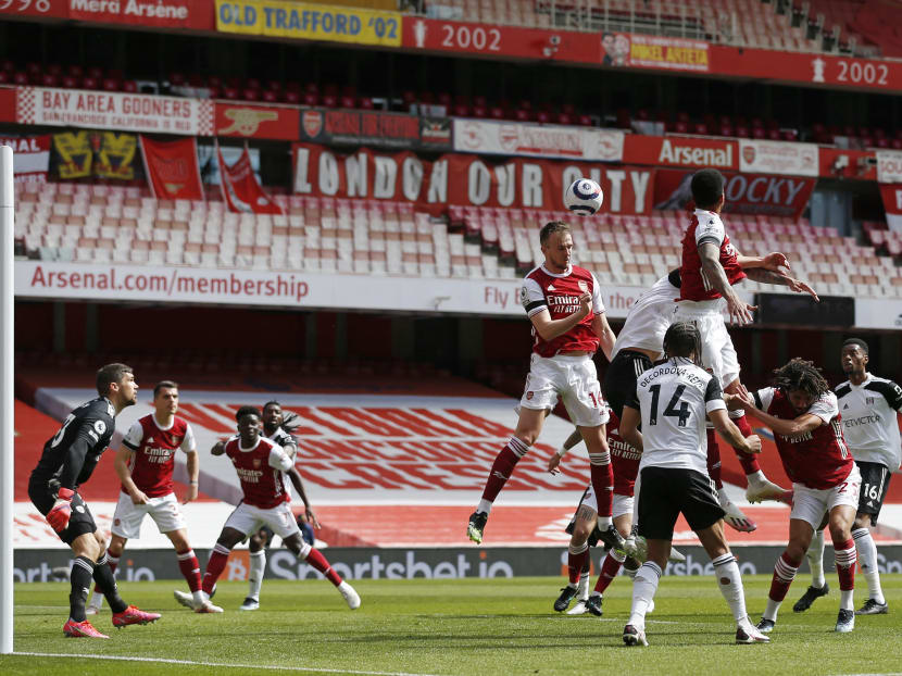 Arsenal's English defender Rob Holding (centre) makes a defensive header during the English Premier League football match between Arsenal and Fulham at the Emirates Stadium in London, UK on April 18, 2021.