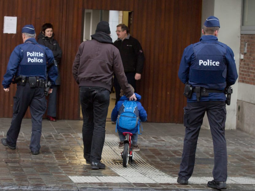 A man wheels a boy on his bicycle past police officers as they arrive for school in the centre of Brussels on Nov 25, 2015. Photo: AP