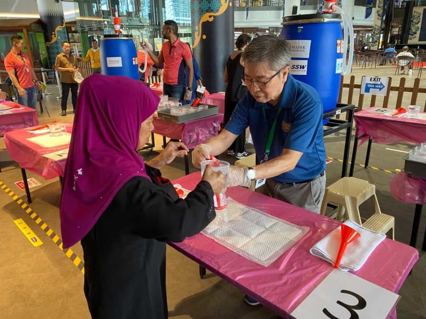 A volunteer from RSVP Singapore, an organisation of senior volunteers, helping members of the public to refill hand sanitisers in March 2020.
