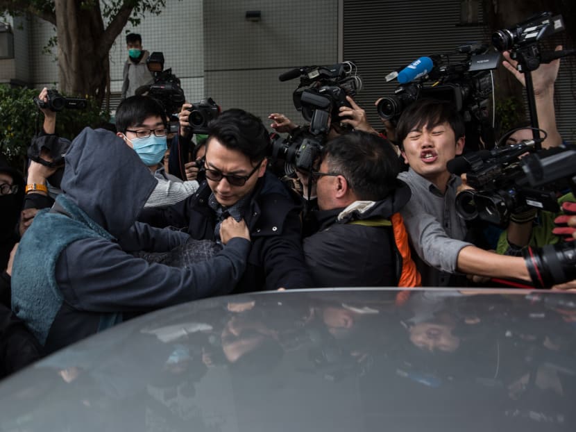 Members of the media jostle for position to cover as supporters help escort a protester (in a grey jacket), who is facing one count of taking part in a riot on Feb 9, 2016 in the district of Mongkok, into a taxi after a court hearing in Hong Kong. Photo: AFP