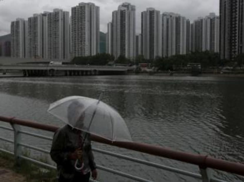 A passer-by walks along a riverside as City One Shatin residential precinct is seen at background in Hong Kong, China. Photo: Reuters
