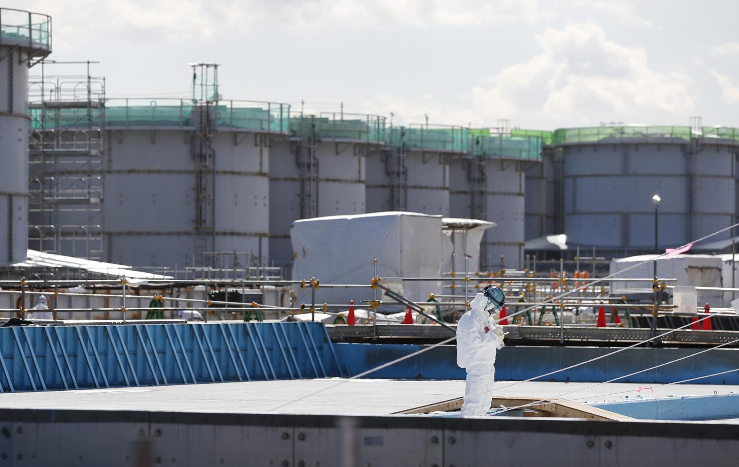 A worker, wearing protective suits and masks, takes notes in front of storage tanks for radioactive water at Tokyo Electric Power Co's (TEPCO) tsunami-crippled Fukushima Daiichi nuclear power plant in Okuma town, Fukushima prefecture, Japan Feb 10, 2016. 