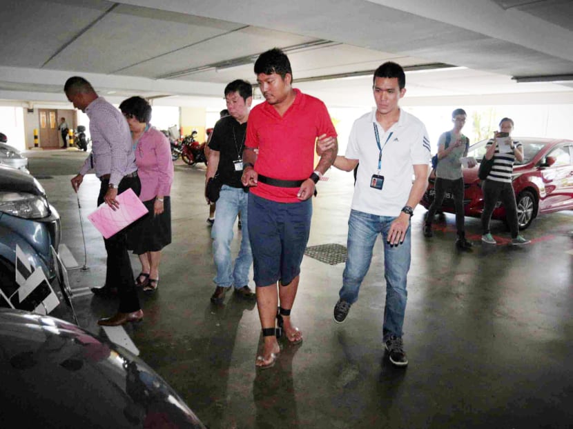 Phyo Min Naing (in the red shirt), 31, charged with conspiring to commit murder, revisits the crime scene with investigators of the SPF and an interpreter at the multi storey carpark at 747A Pasir Ris Street 71. TODAY file photo