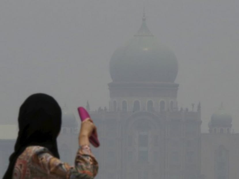 A woman looks towards the Prime Minister's office, which is shrouded in haze, in Putrajaya, Malaysia October 6, 2015. Photo: Reuters