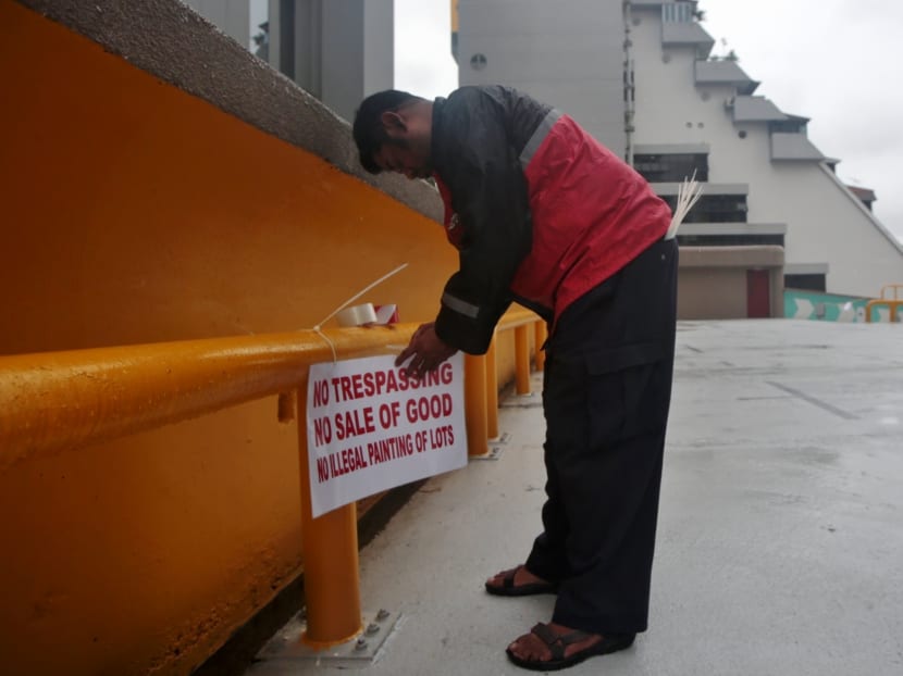 A man putting up a sign prohibiting the sale of goods at the Golden Mile carpark. Photo: Jason Quah/TODAY