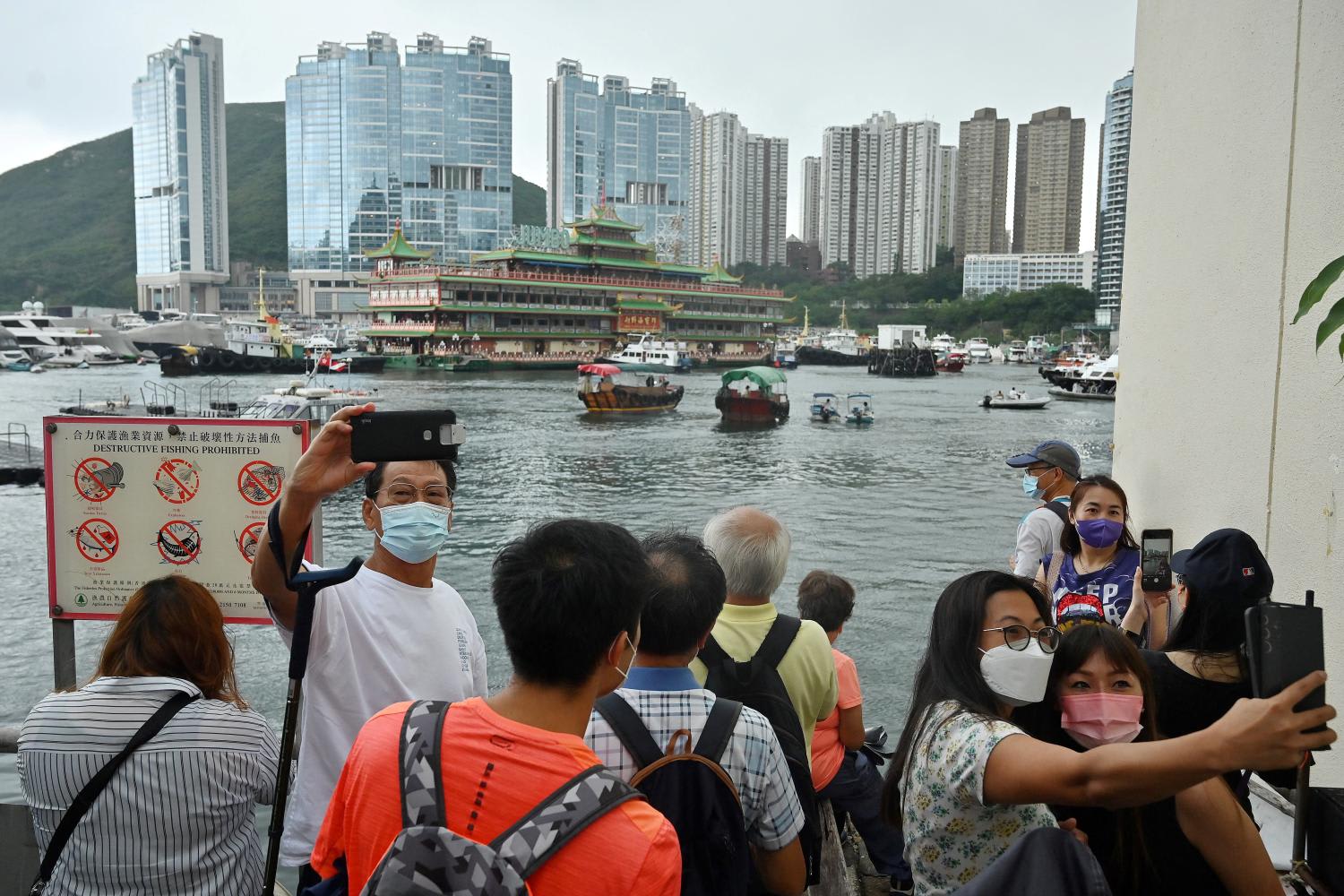 Onlookers taking photos as Hong Kong's Jumbo Floating Restaurant was towed out of Aberdeen Harbour on June 14, 2022.