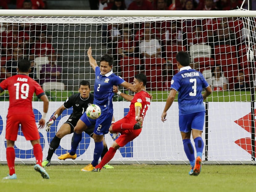 Singapore's Mohammad Shahril Bin Ishak attempts a shot on goal as Thailand's Perapat Notechaiya attempts to block during their AFF Suzuki Cup Group B soccer match in Singapore, Nov 23, 2014. Photo: AP