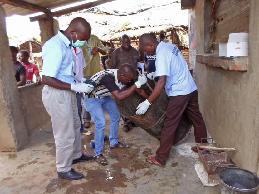Mozambique government officials gather samples from a drum that was used to brew traditional local beer that killed 69 people in Tete, Mozambique, Jan 12, 2015. Photo: AP