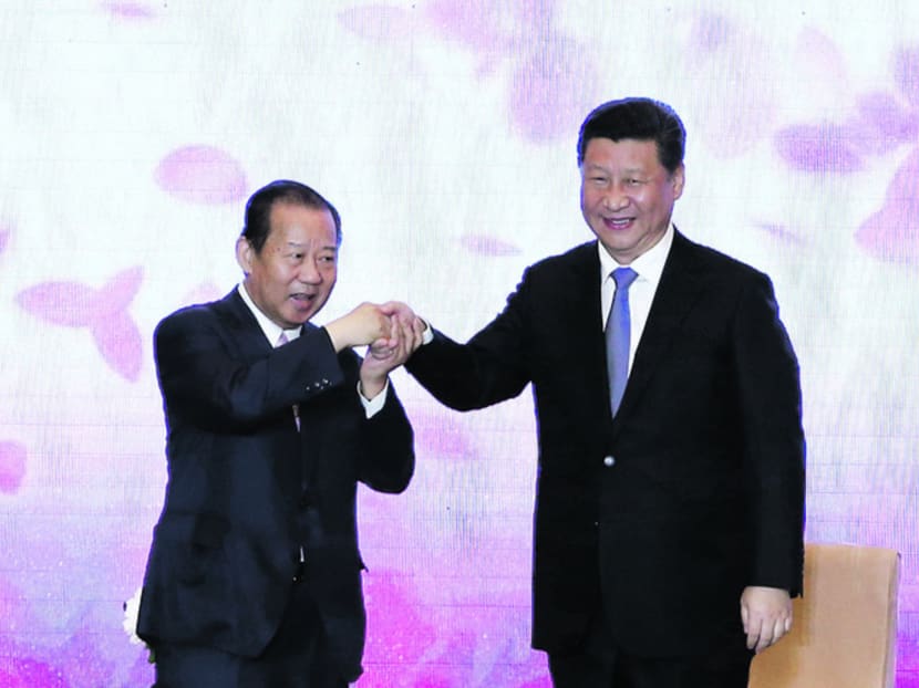 Mr Xi (right) holding hands with Mr Nikai during the China-Japan friendship exchange meeting yesterday. Photo: Reuters