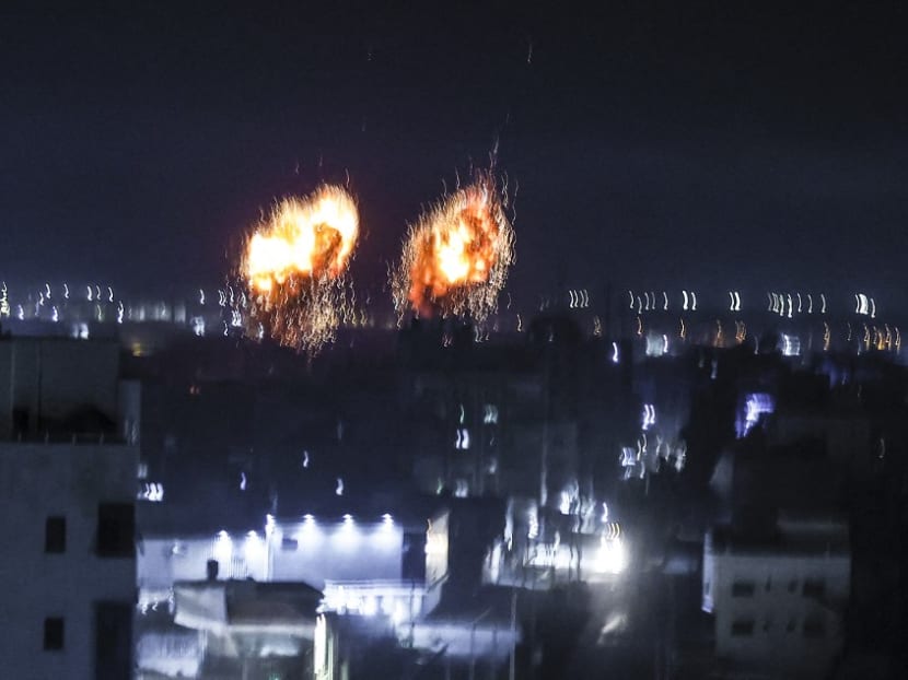 Explosions light-up the night sky above buildings in Gaza City as Israeli forces shell the Palestinian enclave, early on June 16, 2021.