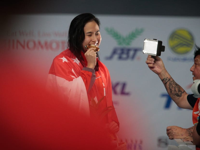 Quah Ting Wen obliging a media request to bite her gold medal for a photo after her race . Photos: Jason Quah/TODAY