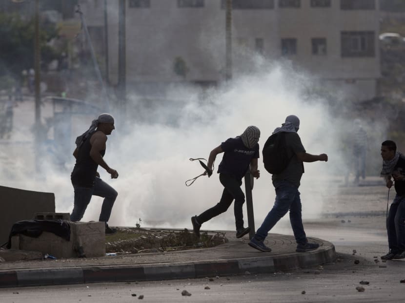 Palestinians run from tear gas during clashes with Israeli troops near Ramallah, West Bank, Oct 12, 2015. Photo: AP