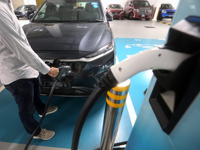 An electric vehicle owner charging his car at a charging station located in a carpark on Feb 25, 2021.