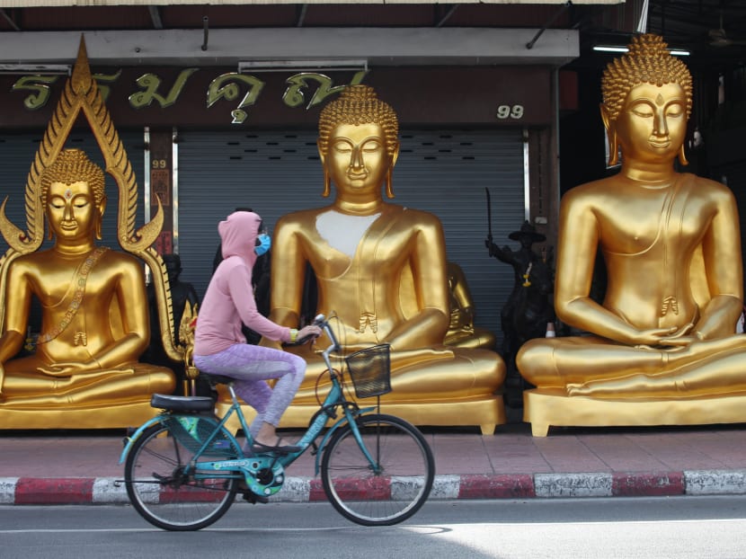 A woman pedals past a shop on Siriphong Road in the heart of Bangkok's historic Rattanakosin Island area on April 19,2020.