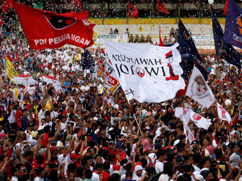 Party flags are seen during a campaign rally of President Joko Widodo at a stadium in Banten province in March. The author says that both the Widodo and Subianto camps pervasively used Islamic symbols of piety during their campaigns.
