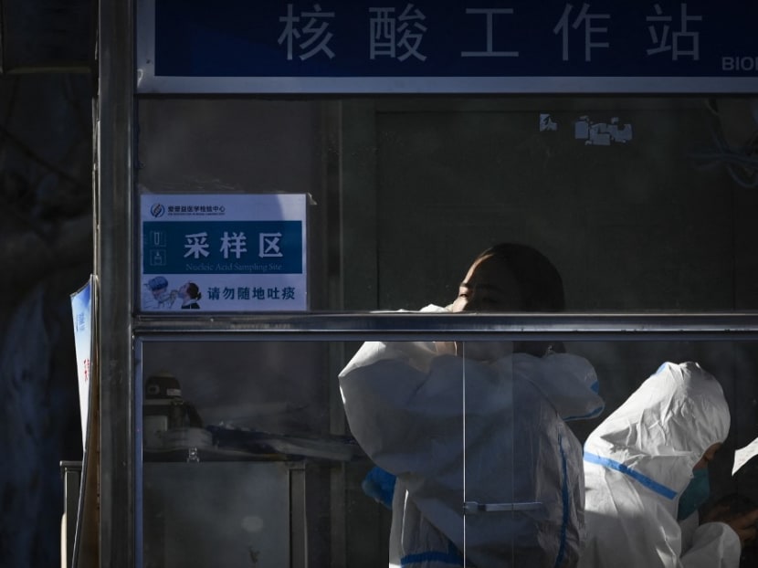 A health worker watches as she sets up inside a testing booth for Covid-19 in Beijing on Dec 5, 2022. A health worker watches as she sets up inside a testing booth for Covid-19 in Beijing on Dec 5, 2022.