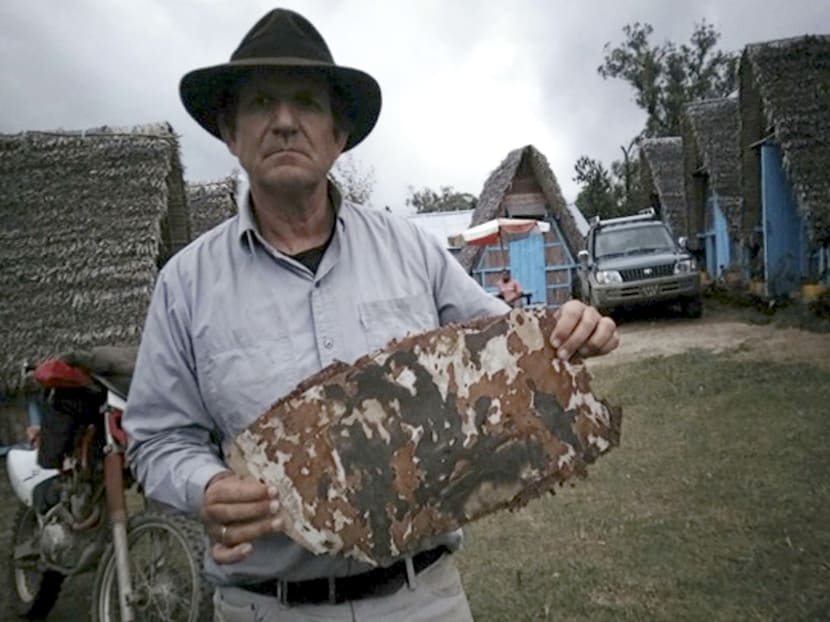 This Sept. 17, 2016 photo supplied by Blain Gibson shows him holding a piece of aircraft debris on a beach in Madagascar. Gibson is the first person searching for the plane who’s actually found any trace of it and says he won’t quit gathering clues until the mystery is solved. Photo via AP