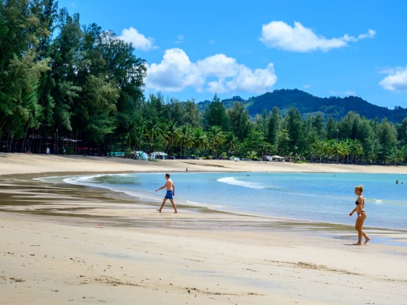 Tourists walk on a beach on the Thai island of Phuket on Nov 1, 2021, as Thailand welcomes the first group of tourists fully vaccinated against the Covid-19 coronavirus without quarantine.
