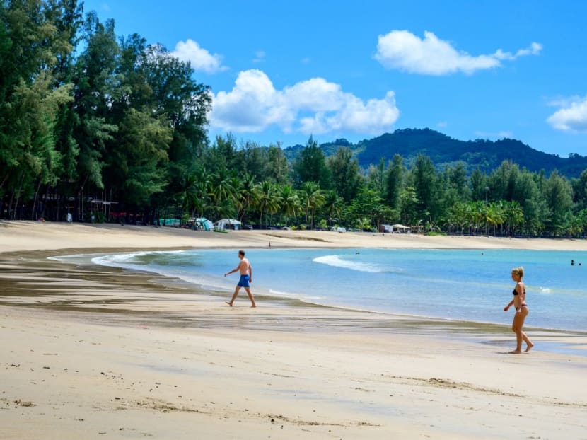 Tourists walk on a beach on the Thai island of Phuket on Nov 1, 2021, as Thailand welcomes the first group of tourists fully vaccinated against the Covid-19 coronavirus without quarantine.
