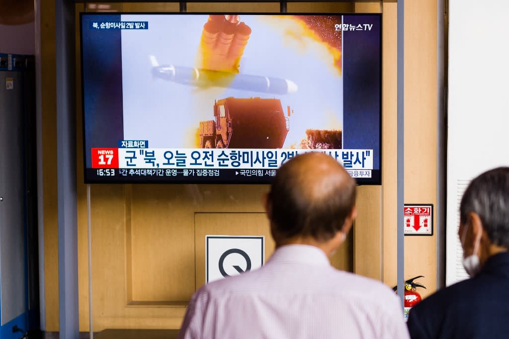 People sit near a screen showing a news broadcast with file footage of a North Korean missile test, at a railway station in Seoul on August 17, 2022, after North Korea fired two cruise missiles.