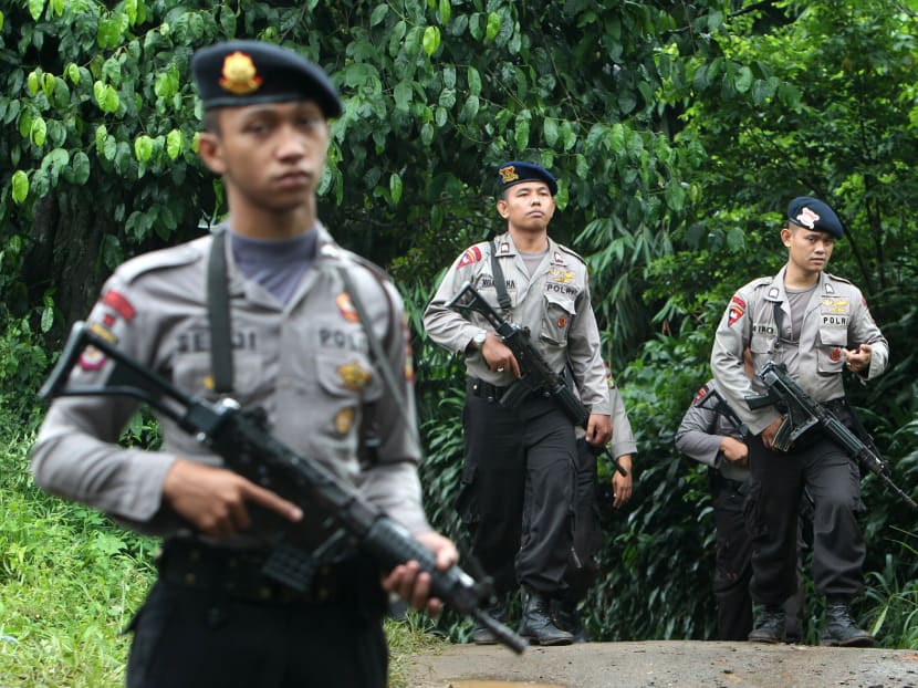 Police officers patrol the area near a house that was used as a hideout by suspected militants following an overnight raid in Ciputat, Indonesia. Photo: AP