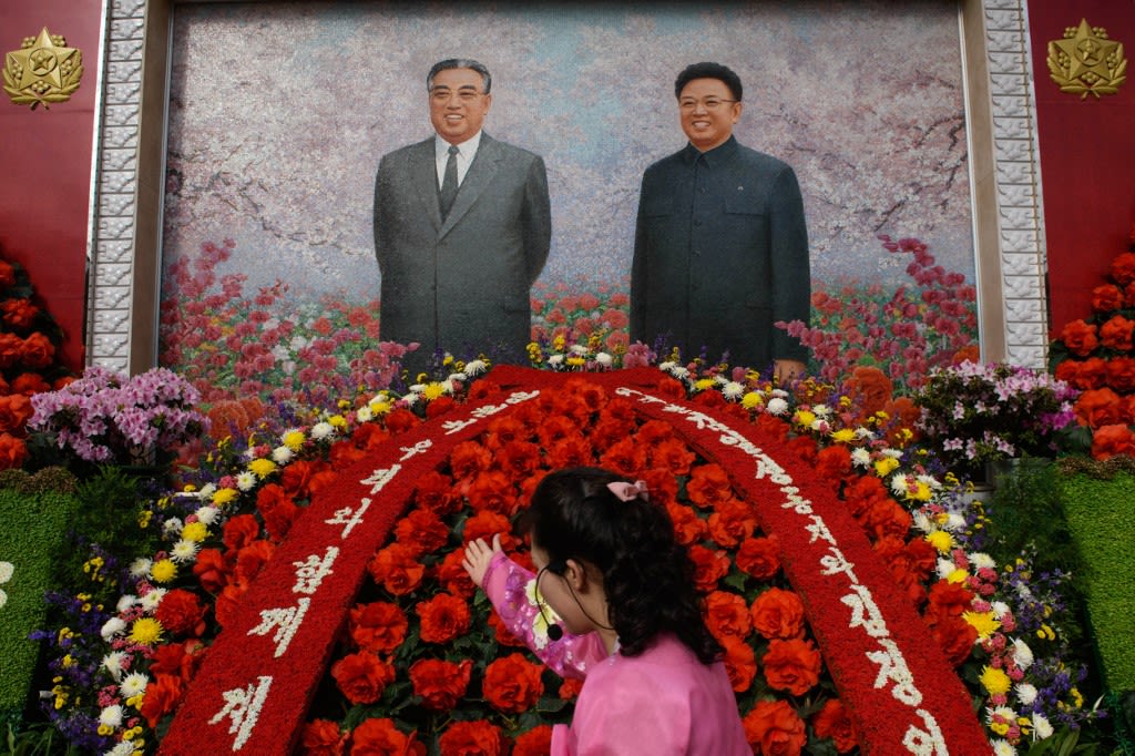 A guide gestures before the portraits of late North Korean leaders Kim Il-sung and Kim Jong-il during a "Kimjongilia" flower exhibition celebrating late leader Kim Jong-il, in Pyongyang on Feb 14, 2019.