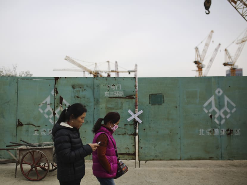 A woman wearing a mask walks past a closed construction site at the Central Business District in Beijing, China Nov 11, 2014. Photo: AP
