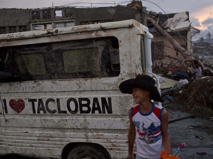 In this Nov 21, 2013 photo, a Typhoon Haiyan survivor walks near a minivan with the words "I Love Tacloban" painted on the side in a destroyed village in Tacloban, Philippines. Photo: AP
