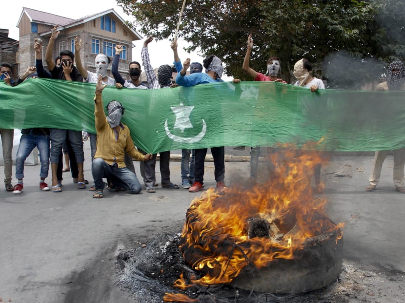 Masked Kashmiri protesters shout slogans displaying Pakistani flag soon after the authorities lift the curfew in Srinagar, Indian controlled Kashmir, Tuesday, July. 26, 2016. Shops and businesses remained shut due to a strike called to protest Indian rule in the Himalayan region. Photo: AP