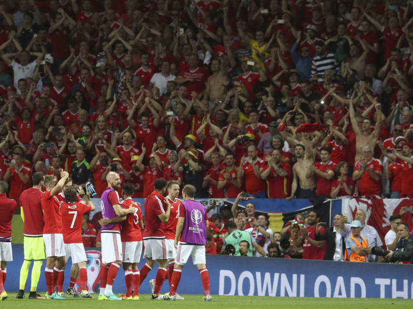 Wales players celebrating in front of their fans after winning 3-0 against Russia. Wales have earned their place in the last 16 through group effort. Photo: AP
