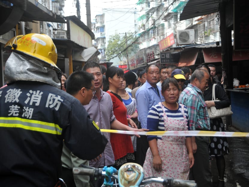 Bystanders watch as firemen work to put out a fire following an explosion in a restaurant in Wuhu city in eastern China's Anhui province, on Oct 10, 2015. Photo: Chinatopix via AP