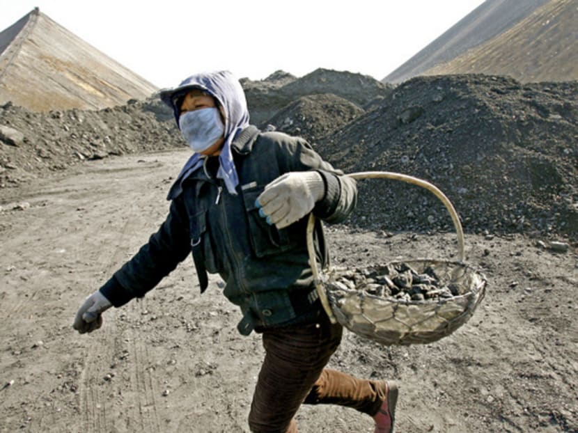 A labourer hauling useable coal at a cinder dump site at Daming Coal Mine in Diaobingshan, Liaoning. Photo: Reuters