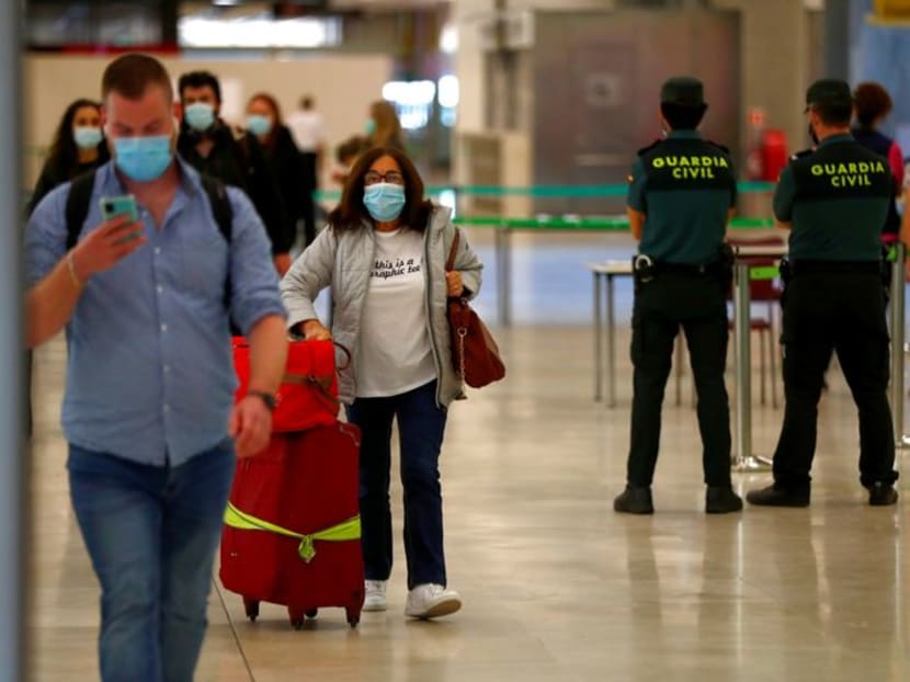 FILE PHOTO: Guardia Civil officers watch as passengers, wearing protective face masks, walk upon arrival from Paris at Adolfo Suarez Barajas airport as Spain reopens its borders to most European visitors after the coronavirus lockdown, in Madrid, Spain, June 21, 2020. REUTERS/Sergio Perez