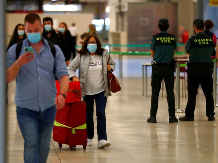 FILE PHOTO: Guardia Civil officers watch as passengers, wearing protective face masks, walk upon arrival from Paris at Adolfo Suarez Barajas airport as Spain reopens its borders to most European visitors after the coronavirus lockdown, in Madrid, Spain, June 21, 2020. REUTERS/Sergio Perez FILE PHOTO: Guardia Civil officers watch as passengers, wearing protective face masks, walk upon arrival from Paris at Adolfo Suarez Barajas airport as Spain reopens its borders to most European visitors after the coronavirus lockdown, in Madrid, Spain, June 21, 2020. REUTERS/Sergio Perez