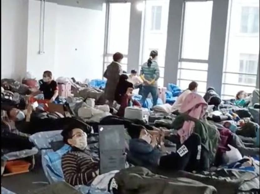 A man uses a laptop while people rest at a quarantine centre near Linkong Skate Park in Changning District, Shanghai, China in this still image from a social media video obtained by Reuters on April 14, 2022.