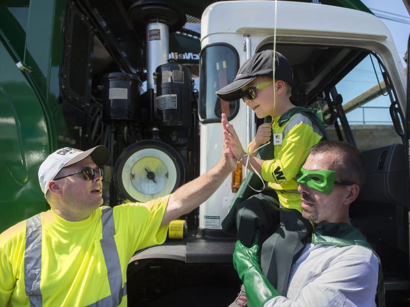 Six-year-old Ethan Dean, who was diagnosed with cystic fibrosis at two weeks old, gets a high five while carried by Capt. Recycle, Mitch Zak during his stop at The Sacramento Bee to pick up recycling as part of his Make-A-Wish Foundation activity. Photo: AP