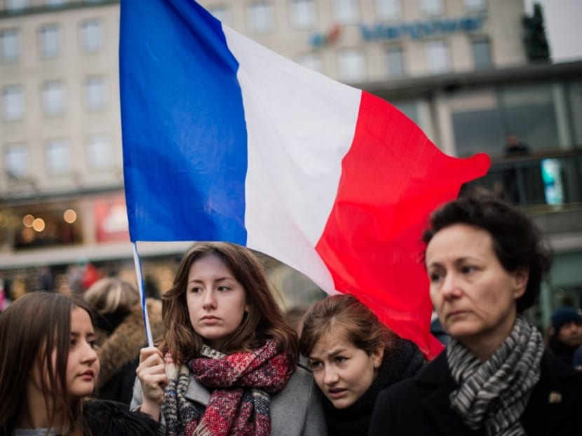 A woman holds a flag of France during a gathering in solidarity for France a day after deadly attacks in Paris on November 14, 2015 in Stockholm. Two Swedish citizens may be among the victims of the attacks that killed more than 120 people in Paris, the foreign ministry said. Photo: AFP