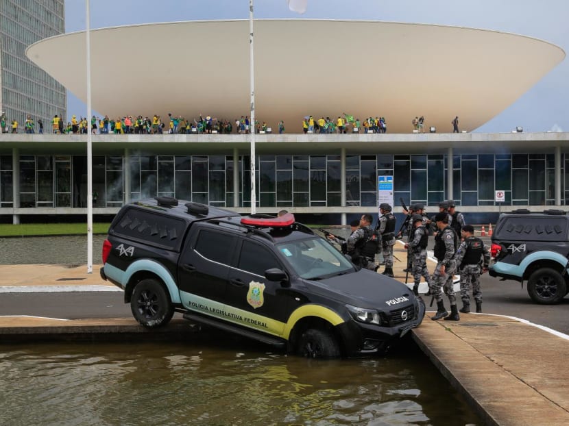 Members of the Federal Legislative Police stand next a vehicle that crashed into a fountain as supporters of Brazilian former President Jair Bolsonaro invade the National Congress in Brasilia on Jan 8, 2023.