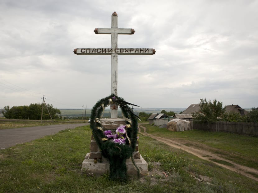 A wreath is placed on a cross with an inscription that reads "Save and protect" next to the site of the downed Malaysia Airlines flight MH17, near the village of Hrabove (Grabovo) in Donetsk region, eastern Ukraine, July 14, 2015.  Photo: Reuters