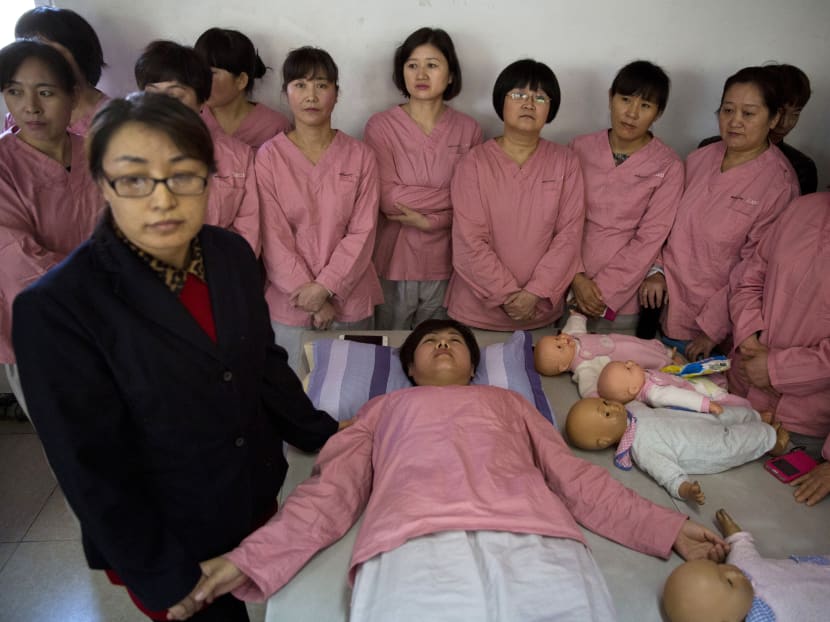 A maternity matron pose as a pregnant mother during classes run by Li Ming Maternity Service Company in Beijing, China. Photo: AP