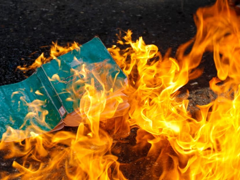 A copy of the 2008 constitution is burnt as protesters take part in a demonstration against the military coup in Yangon's Kyimyintdine township on April 1, 2021. A copy of the 2008 constitution is burnt as protesters take part in a demonstration against the military coup in Yangon's Kyimyintdine township on April 1, 2021.