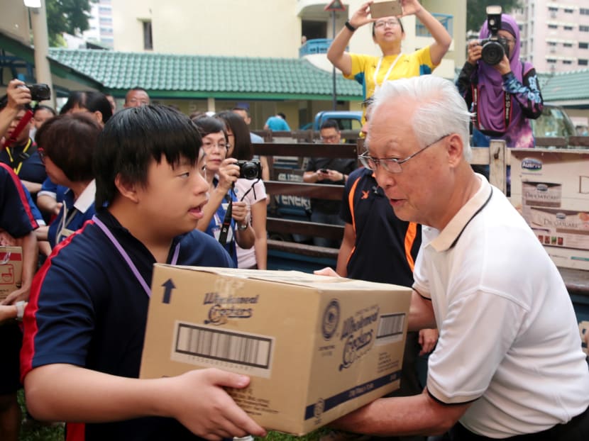 MINDS student Nathan Tan passes a box of biscuits to ESM Goh Chok Tong during the One Community Day 2017 @ Marine Parade GRC Project on Jan 15, 2017. Photo: Jason Quah/TODAY