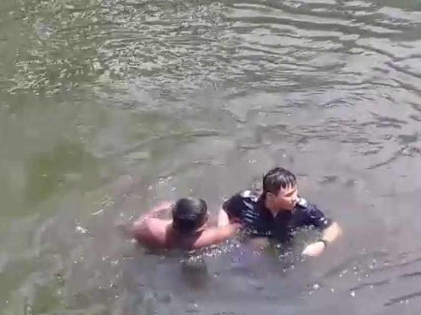 Rajendran Prakash, 27, (left) pictured in the Rochor Canal with a police officer who was rescuing him after he drunkenly harassed churchgoers then jumped in the canal. He later verbally abused police, the court heard.