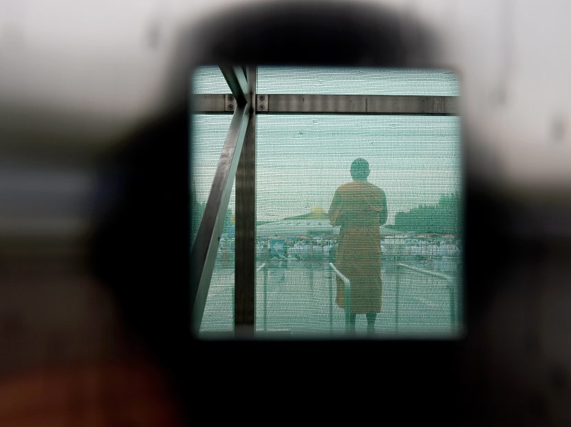 A monk from the controversial Wat Dhammakaya temple is seen through the closed and netted gate as supporters gather at the temple grounds in northern Bangkok on June 16, 2016. Photo: AFP