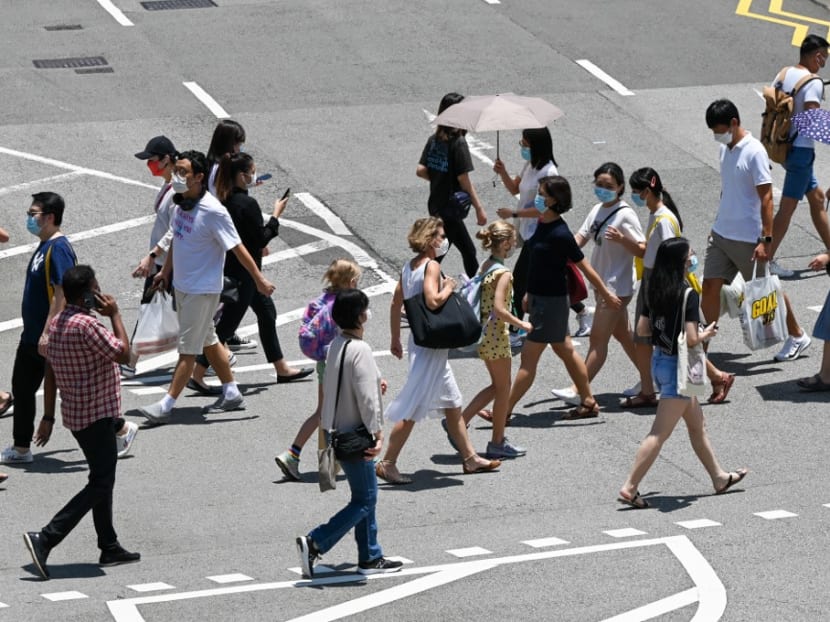 People walk at a pedestrian crossing along the Orchard Road shopping district in Singapore.
